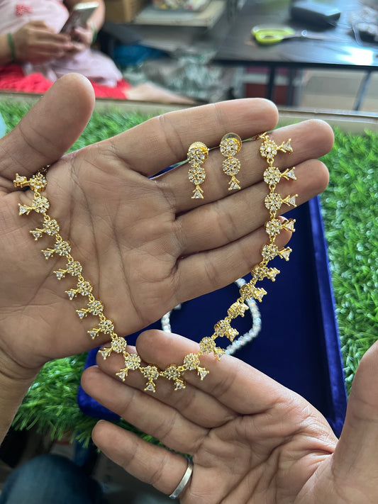 Gold necklace and earrings held in a hand with a blurred background