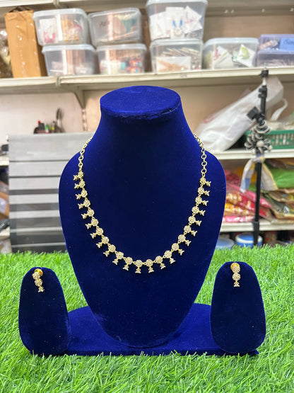 Necklace and earrings set on a blue velvet stand with a store shelf in the background